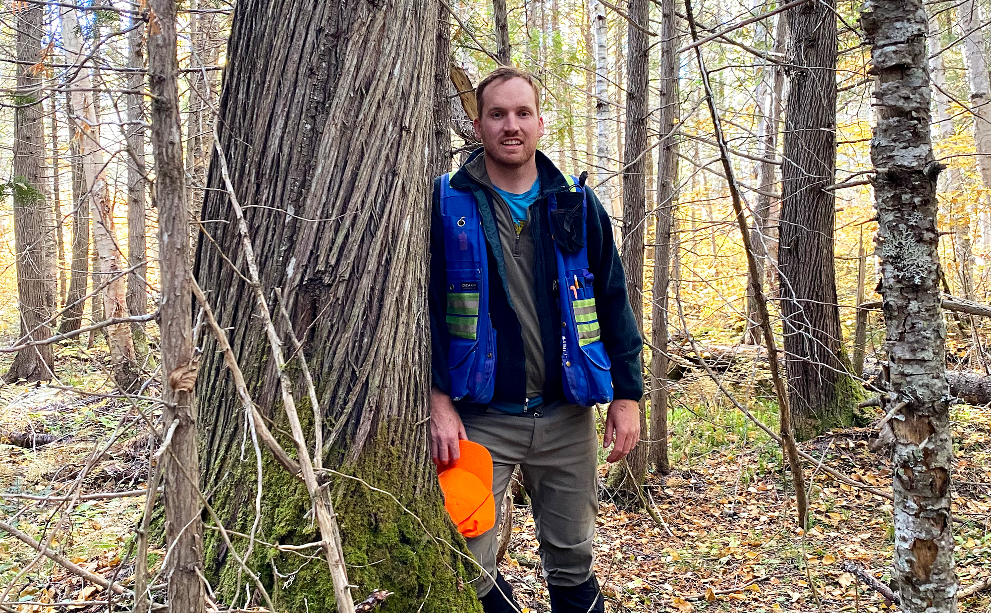 Shawn McGrath leaning against a tree in the forest.